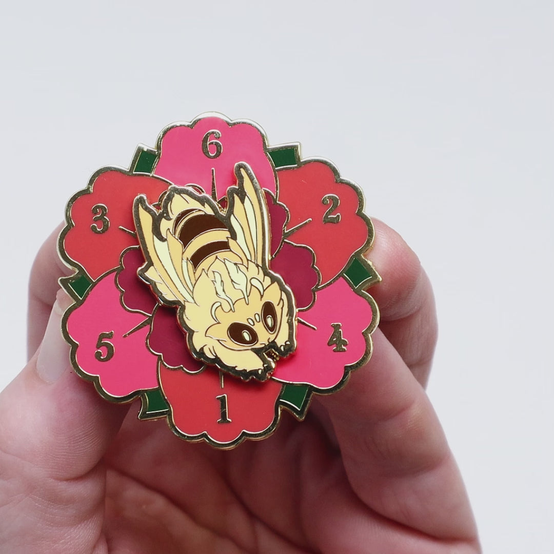 A video of enamel pin of a bee on a flower that spins.